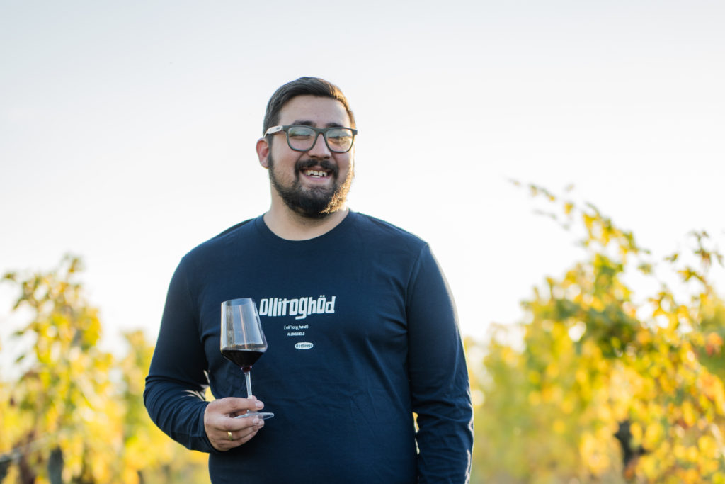OstSeele - textile Mundart - Mann lächelt und hält ein Glass Wein